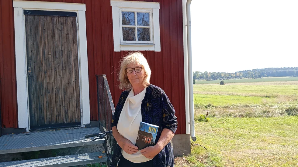 Romandebuterande Solveig Pettersson framför bystugan i Åloppe. Hon är noga med att påpeka att boken inte handlar om Åloppe och dess invånare.