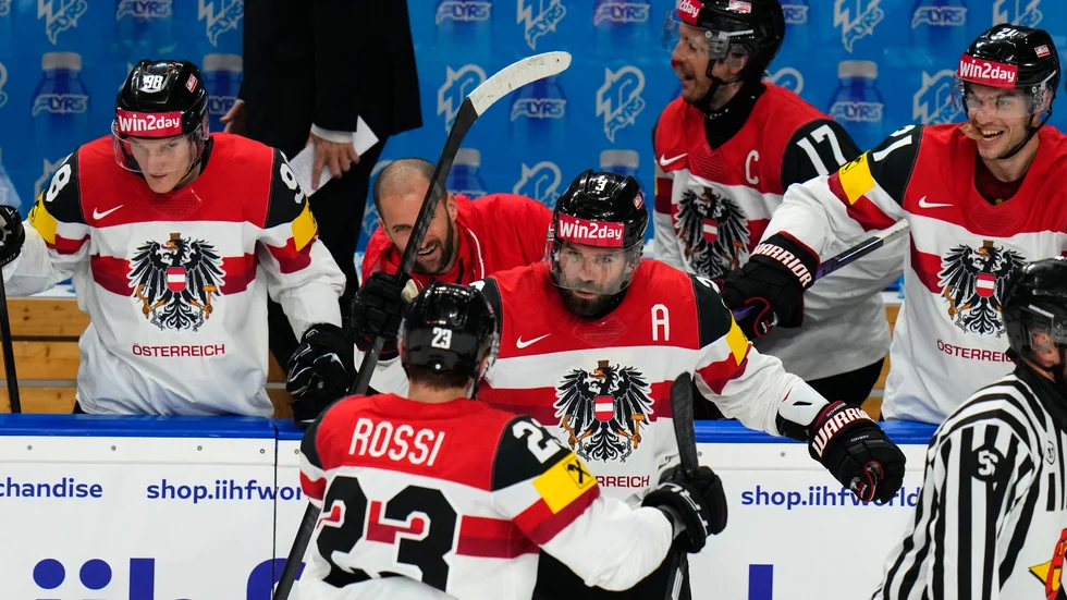Österrikes tvåmålsskytt Peter Schneider, i mitten, jublar och gratuleras av NHL-forwarden Marco Rossi, Minnesota.