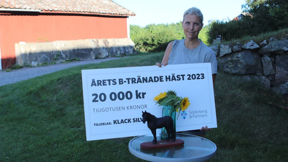 Anna Frössevi Ericsson visar stolt upp beviset på att hon har landets bäst b-tränade häst 2023, en utmärkelse som hon fick motta vid årets Elitsloppsgala på Solvalla.