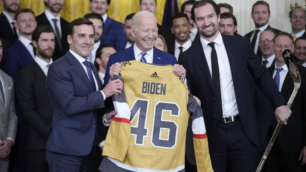 President Joe Biden med en Vegas-tröja. Vegas-kaptenen Mark Stone till höger, överlämnade även en hockeyklubba.