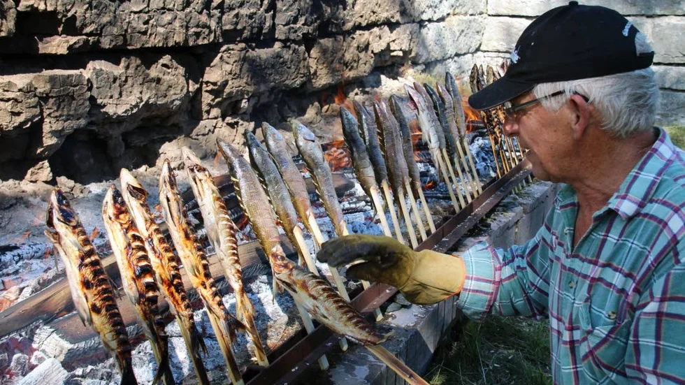 Guy Eriksson grillar fisk för att tillgodose alla besökare som köar för att få handla.