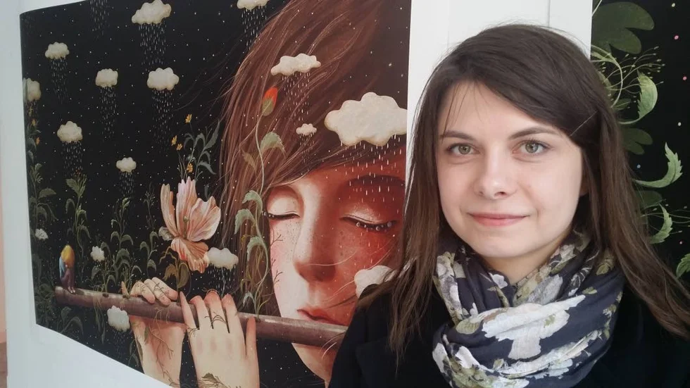 Emilia Dziubak i Stockholm med en av sina målningar som ingår i barnboken "Lilla Sticka i landet Lycka".