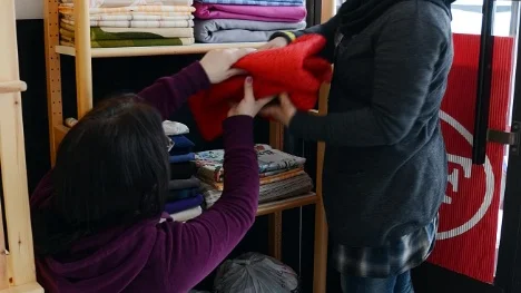 Luliia Islami och Fatima Kaniz packar upp tyger som allmänheten har skänkt till de nystartade kurserna i sömnad.