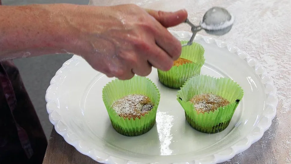 En lätt pudring av florsocker innan den östgötska hallonmuffinsen med vit choklad är klar att förtäras.