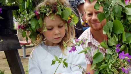 Minou Niklasson, 4, hjälpte till och stoppade blommor i majstångens krans. I bakgrunden syns pappaThomas Simonsson.                                                                                                                                                           FOTO: LENA LEFFLER