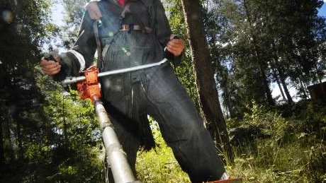 Arbetsledare Steve Johansson röjer sly med röjsåg intill brandstationen i Västervik.