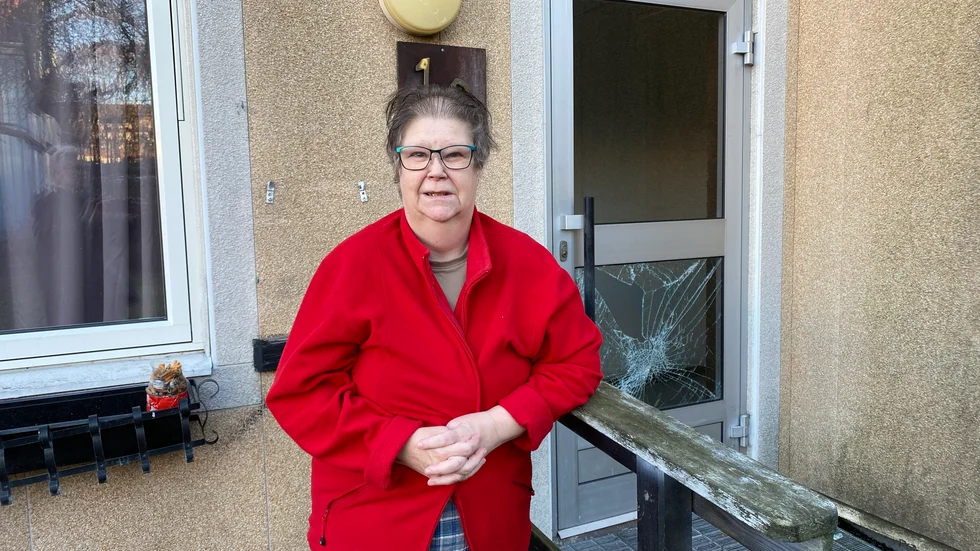 Åsa Klintberg intygar att husen är slitna och visar rutan i ytterdörren i porten intill hennes. Hon berättar också om råttor, sunkig tvättstuga och avloppslukt. 