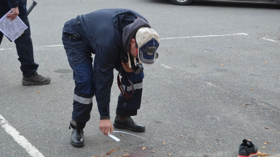 Dokumenterar. Polisen mäter storleken på den blodsamling som fanns på asfalten.