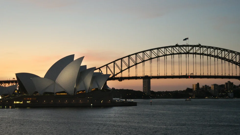 Operahuset i Sydney i skymning framför Harbour Bridge.