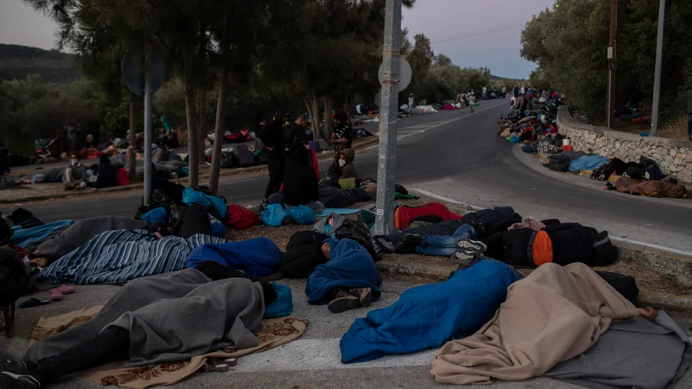 Flyktingar längs vägen utanför det nedbrunna lägret på Lesbos.