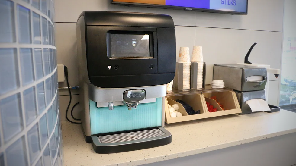 Efter helgens avstickare ut på parkeringen står nu kaffeautomaten på sin vanliga plats intill muggarna och ketchupen.