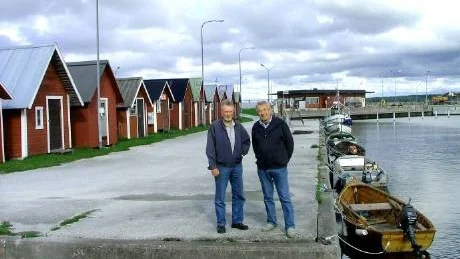 FISKEHAMN. Kjell och Åke Broberg protesterar mot kommunens beslut att sälja hamnen i Kappelshamn. Här står de i fiskehamnen, och i bakgrunden syns stora hamnen med hamnstationen som inrymmer restaurang.