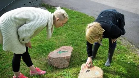 Maria Ragnestam och Hanna Nilsson inspekterar gravyren på två av de tolv stenarna som utgör stigen "Gråberg är inte grått".