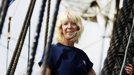 Marita Henningsdotter Lovnér tar på sig sele och klättrar. De vackra seglen hänger i sjok i bakgrunden.