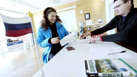 RÖSTADE. Alexander Pashedko, ryska ambassaden i Sverige, kontrollerade först att Angelika Henzh hade behörighet att rösta och gav henne sedan en valsedel som hon placerade i en plomberad låda som öppnas först den 4 mars.Foto: Linda Wikström