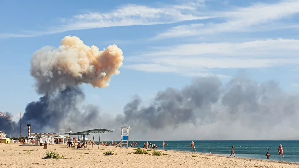 Rökmoln syns från en strand i närheten efter explosionerna vid en rysk militärbas på den ockuperade Krimhalvön.