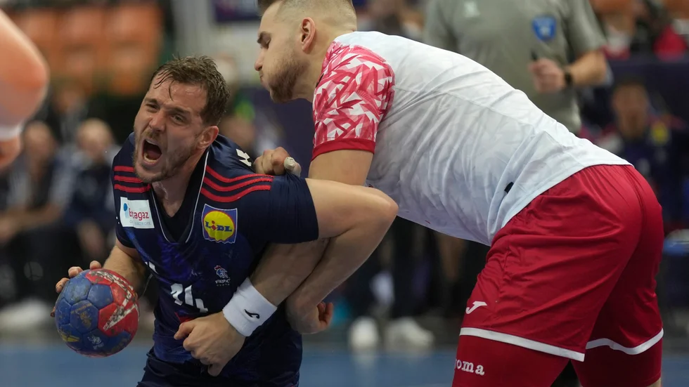 Polens Bartlomiej Bis, till höger, tar ett stadigt grepp om Frankrikes Kentin Mahe i öppningsmatchen i VM. Frankrike vann till slut ändå med 26–24.