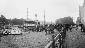 År 1916, skärgårdsbåten Bråviken ska strax tuffa ut till, kan man tänka sig, Arkösund. Hästar och dragkärror, baga-			 ge staplat på kajen. Platsen är utanför Grand (dåförtiden Göta) Hotel. Huset som skymtar till höger står kvar än i dag. Samtliga fotografier på sidan är från Stadsmuseets samlingar.