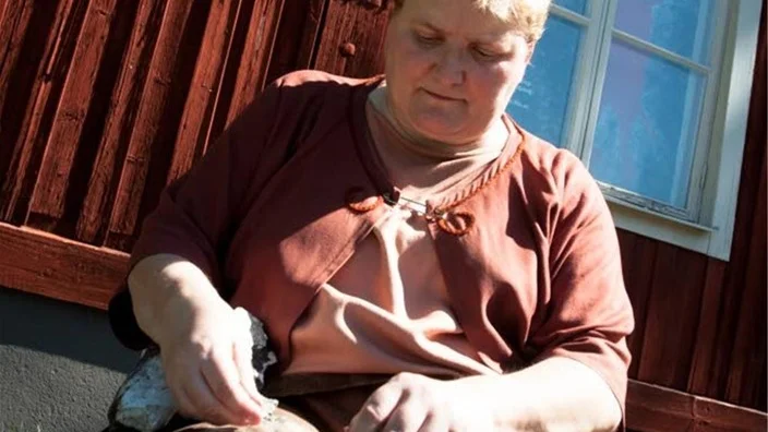 Skinnet skyddar Monica Andersson från de vassa flintaskärvorna. Flintaverktyg kan bli så pass skarpa att de idag börjat användas inom kirurgin.