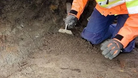 Arkeologen Mats Magnusson frilägger en träkonstruktion från 1350-1550. Under arbetet hittas också hushållskeramik och organiskt material som t ex ben.
