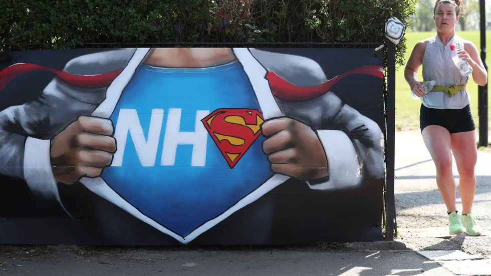 En joggare passerar gatukonst till stöd för vårdsystemet NHS i Hilly Fields Park i London. Bild tagen i påskhelgen.