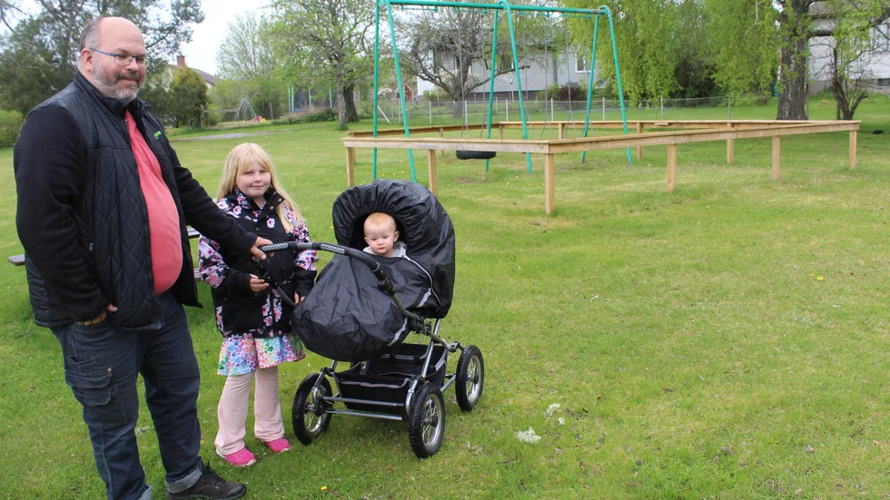 Thomas Wahlstedt med döttrarna Esther och Sally (i barnvagnen) vid den lilla lekparken i Rejmyre.