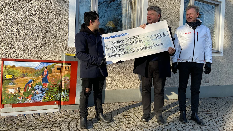 Jalil Rezaei får en check på fem tusen kronor från Åke Serander på Söderköpingsposten och Björn Persson på Eon.
