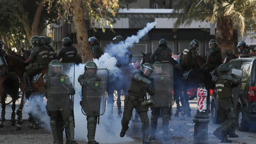 En chilensk polis kastar en tårgasbehållare mot demonstranter under protester i Chiles huvudstad Santiago den 18 december i fjol. Arkivbild.