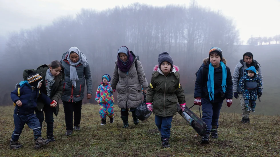 Många migranter som kommit till Bosnien-Hercegovina saknar någonstans att ta vägen. Här vandrar två afghanska familjer i terrängen utanför den bosniska gränsstaden Velika Kladusa, den 10 december. Det är några mil norr om Lipa-lägret.