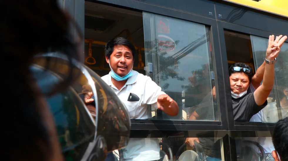 Demonstranter som suttit fängslade i Myanmar vinkar från bussen som fört honom ut från fängelset i Rangoon.
