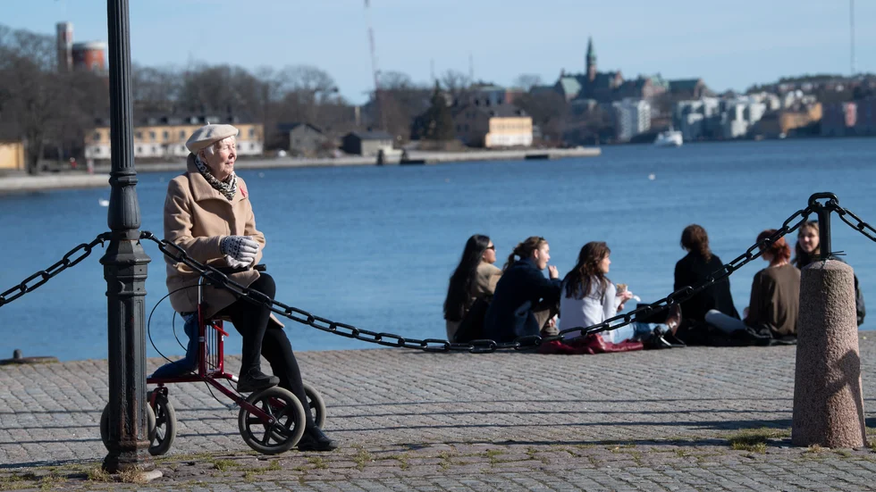 Solsugna huvudstadsbor njuter av vårvärmen på en kaj i Gamla stan i slutet av mars.