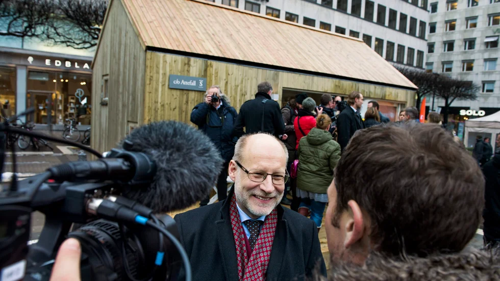 Här ser vi Stefan Attehall, tidigare bostadsminister, som är upphovet till Attefallshuset. I bakgrunden ser vi ett hus av den typen.