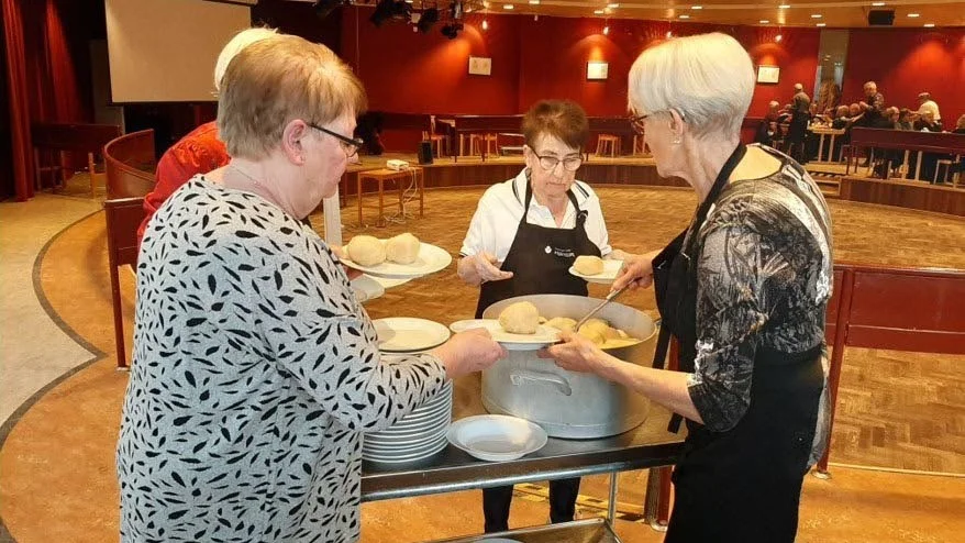 Yvonne Lenman lyfter upp palt från paltgrytan till servitriserna Kerstin Norberg och Ingrid Lundmark.