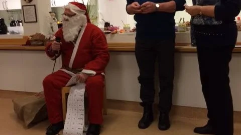 Vinster. Tomten delar ut vinster på tomtelotteriet och flankeras av Stig och Vivianne.