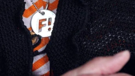 Fi-symbolen hänger om halsen, fast hon gillar den inte riktigt.