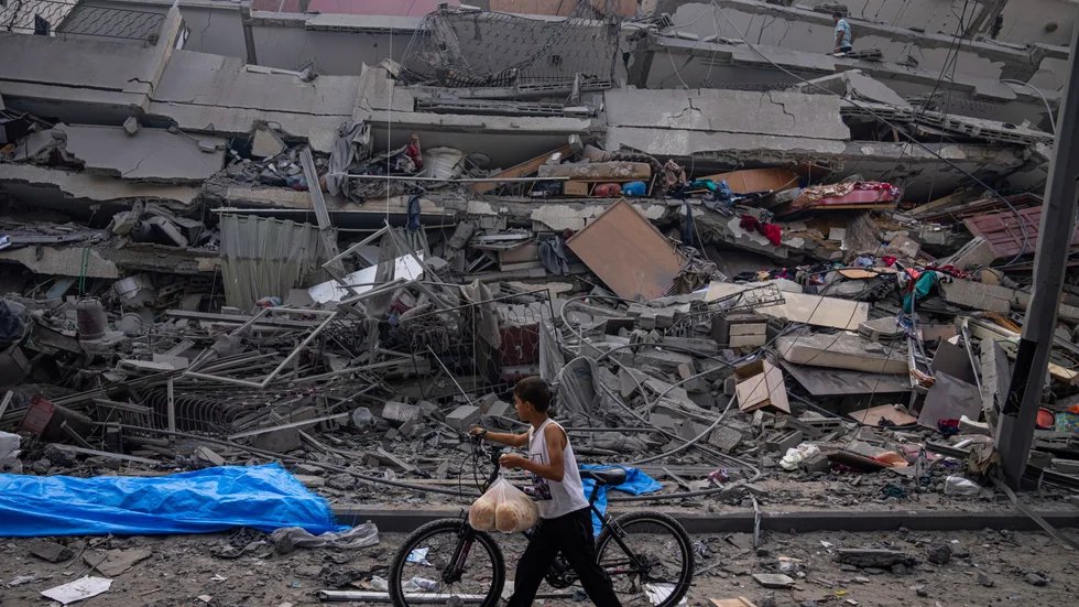 En palestinsk pojke går förbi en sönderbombad byggnad i centrala Gaza med sin cykel.