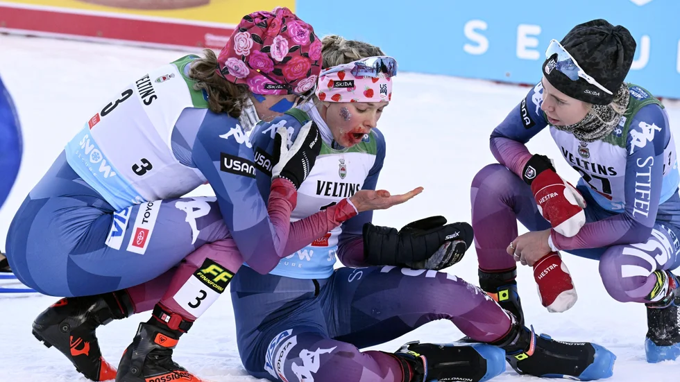 Jessie Diggins, i mitten, får hjälp av sina lagkamrater efter målgången på 20 kilometer fri stil i Ruka.