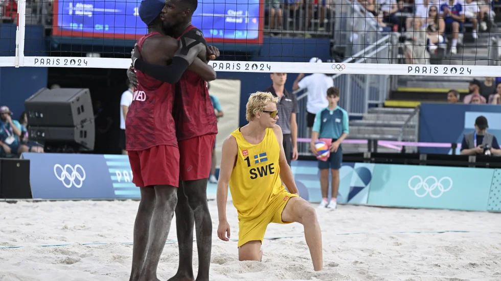 Sveriges David Åhman deppar medan Cherif Younousse och Ahmed Tijan från Qatar firar segern i måndagens gruppspelsmatch i beachvolleyboll under sommar-OS i Paris.