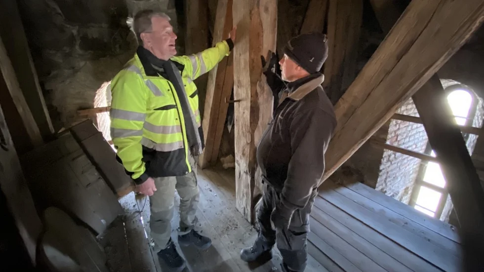 Här inspekterar Peter Staland, från kyrkorådet i Tierps pastorat, och kyrkovaktmästaren Niclas Söderlund en skadad stock i tornet på Västlands kyrka som nu ska rustas upp.