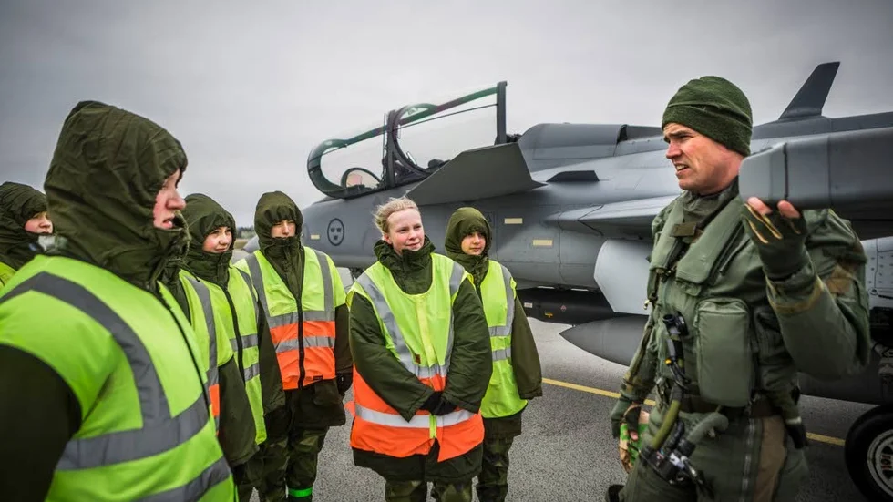 Stridspiloten Filip har flugit från Linköping till Uppsala. Elin Sundelin från Kalix, utan luva, lyssnar uppmärksamt när han demonstrerar en antenn på sitt Jasplan.
