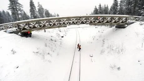 NY SKOTERBRO. På onsdagen fick Niemisel en ny passage över Haparandabanan - en 27 meter lång och 19 ton tung träbro från Skellefteå. Den nya skoterbron säkrar trafiken på Malmens väg och ersätter en gammal, farlig överfart vid stationen i Niemisel.Foto: ROLAND S. LUNDSTRÖM