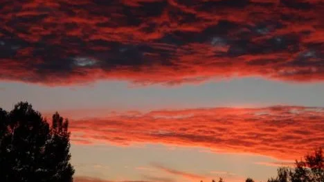 Solen färgar molnen över Stockfors i starka färger, sedan den gått ner bakom bergen.