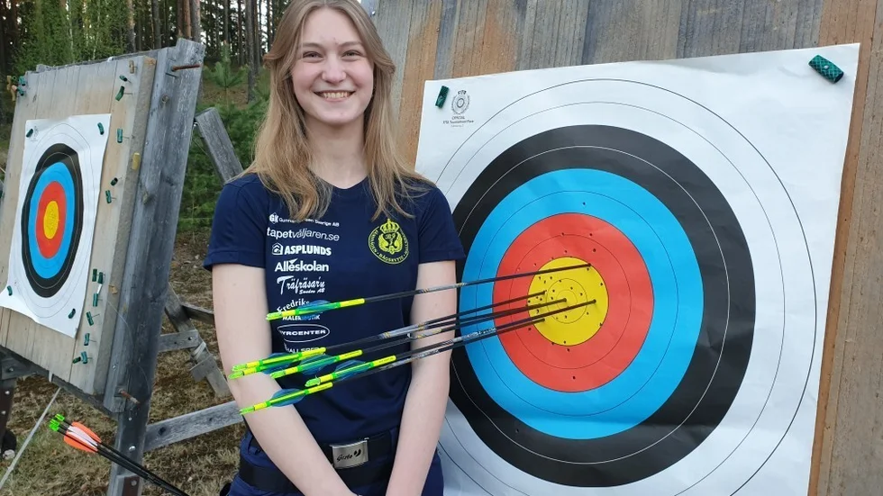 Tilde Ottosson framför tavlan där hon satte nytt svenskt juniorrekord i bågskytte.