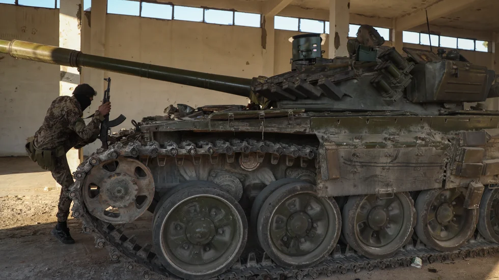 En milisman vid syrisk arméutrustning som övergivits i Maarat al-Numan nära Aleppo på lördagen.