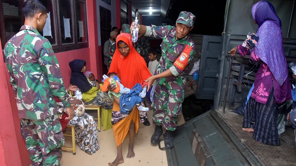 Indonesiska soldater hjälper kvinnor och barn upp på en militärbil efter att de har varit fast till sjöss i flera veckor.