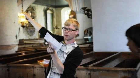 Dirigenten Alexander Einarsson hänvisar körmedlemmar till olika platser i kyrkan.