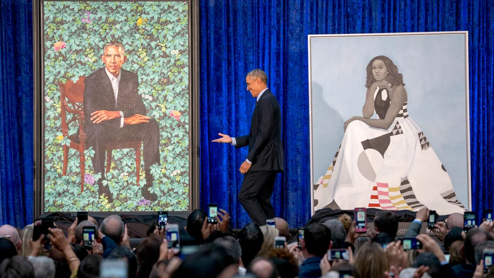 USA:s tidigare president Barack Obama och porträttet på honom av konstnären Kehinde Wiley när målningen presenterades 2018. Till höger det officiella porträttet på Michelle Obama. Arkivbild.