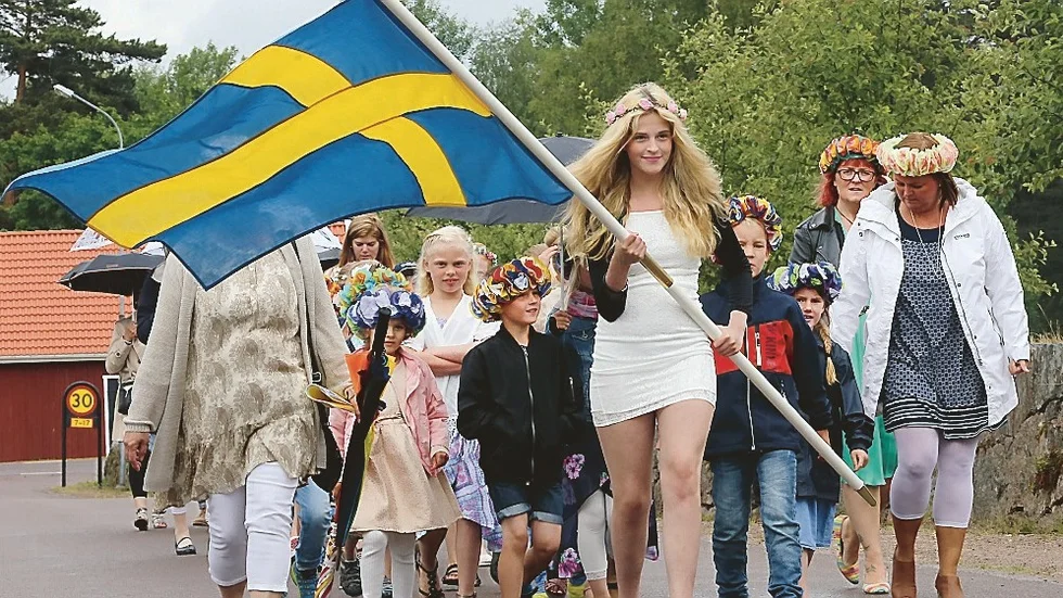 Här en bild från en traditionell skolavslutning i Rumskulla Kyrka. Alla elever med My Johansson i spetsen med svenska flaggan gick i kortege från skolan till  kyrkan medan kyrkklockorna ringde.Efter psalmen ”En vänlig grönskas rika dräkt” hölls en kort  betraktelse och med Idas Sommarvisa avslutades skolavslutningen i kyrkan. Typiskt svenskt?