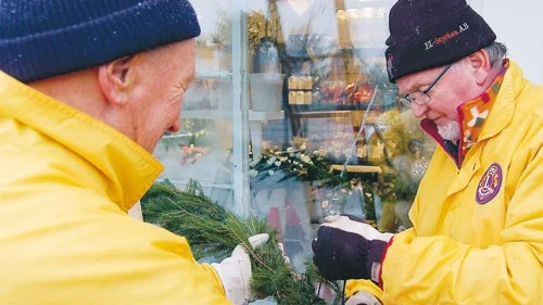 Karl-Göran Karlsson, medlem i norra Tjust Lions Club sätter upp grangirlanger över butikerna i Gamleby.