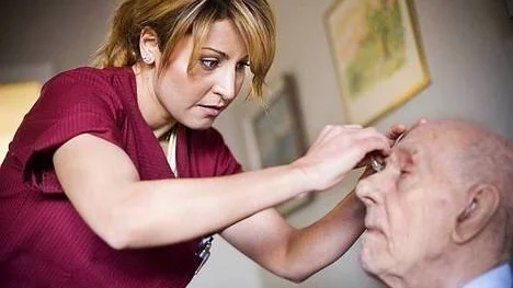 Shilan Zakholi ger ögondroppar till 95 årige Stig Landström som är boende på Björngårdens servicehus.